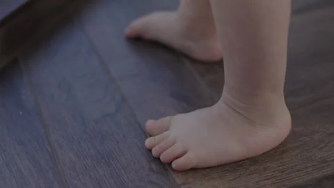Tiny child doing first steps at floor with small cute legs barefoot. Little Stock Footage 271690875