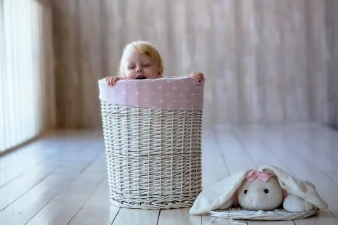 A tiny child eats a dry bun in a basket woven from a wicker tree Foto stock