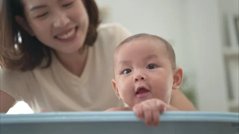 A tiny child enjoys taking a bath in a baby bathtub with mom Stock Footage 289274866