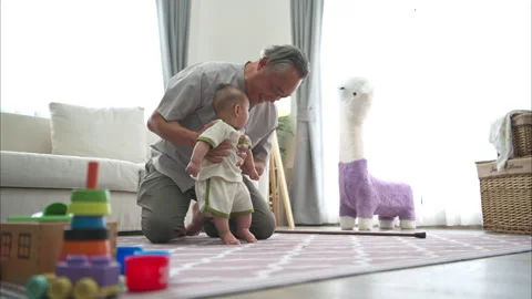 A tiny child practice walking on the floor with grandfather Stock Footage 288019514