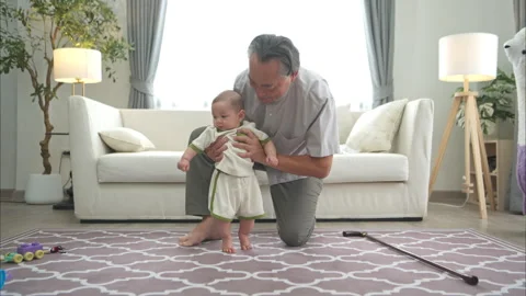 A tiny child practice walking on the floor with grandfather Stock Footage 288103033