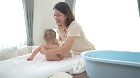 A tiny child smiles happily on the bed waiting for mother apply powder Stock Footage 289280429