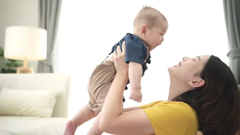 A tiny child smiling happily on the couch in the living room with mom Stock Footage 287969093