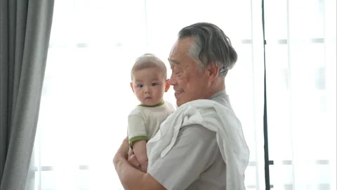 A tiny child smiling happily on the couch with grandfather Stock Footage 288011828