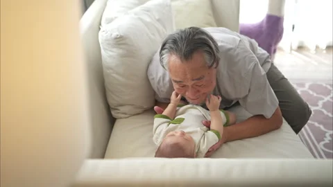 A tiny child smiling happily on the couch with grandfather Stock Footage 288100656