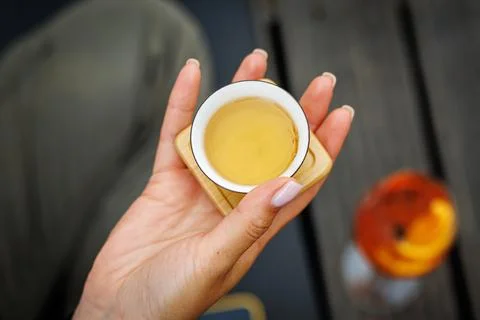 Tiny Chinese teacup in woman's hands during a tea ceremony. Stock Photos