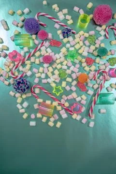 Tiny colorful marshmallows, candy canes, jelly candy, spiral toy and pom poms Stock Photos