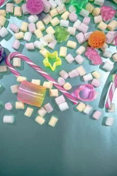 Tiny colorful marshmallows, candy canes, jelly candy, spiral toy and pom poms Stock Photos