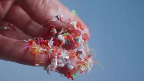 Tiny colorful microplastics fall slowly from fingers, close-up, illustratin.. Stock Footage 289531196