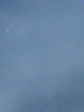 Tiny Crescent Moon in Pale Blue Gray Sky Foto stock