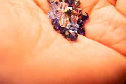 Tiny crystals being held in woman's hand, miniature crystal chips. Macro phot Stock Photos