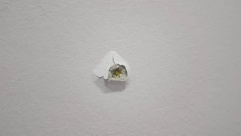 A tiny damage on a white wall reveals plaster and a yellow core Видео 322053110