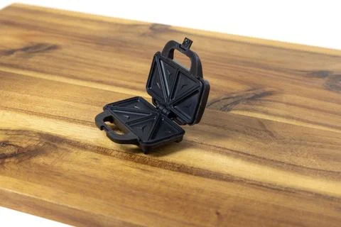 Tiny doll sized sandwich toaster on a wood cutting board side view Stock Photos