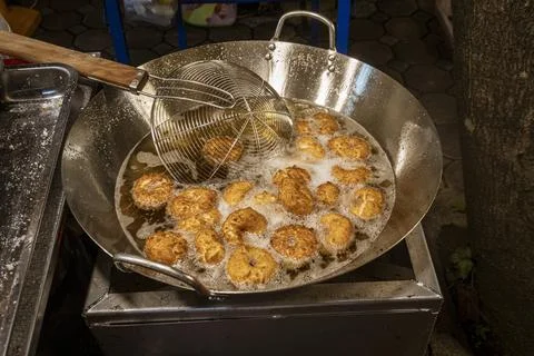 Tiny donuts being cooked at outdoor night street market Stock Photos