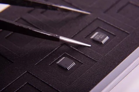 Tiny electronics chip component on the black antistatic mat Stock Photos