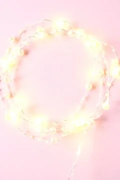 Tiny elegant christmas lights border. Round shape made with garland on pink b Stock Photos