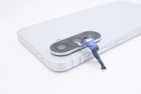 Tiny Figure Pushing Camera Lens on Modern Smartphone Foto stock