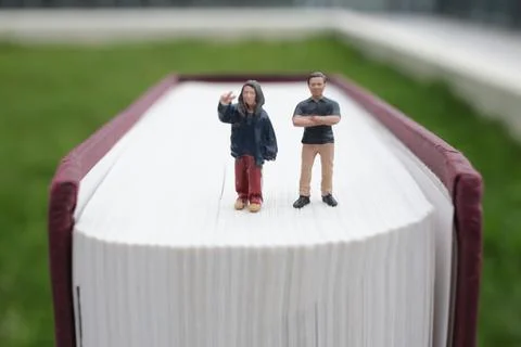 Tiny Figures Stand Firmly Atop Large Textured Book 스톡 사진