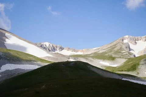 Tiny figures of trekkers walking on top of hill at mountains bottom. 스톡 사진
