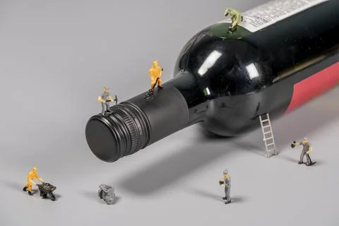 Tiny figures work on a wine bottle in a creative scene Foto stock