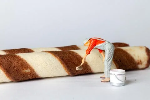 A tiny figurine of a worker in overalls and a cap appears to be painting th.. Foto stock