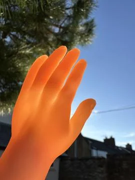 Tiny finger puppet hand toy covering the sun in the sky Stock Photos