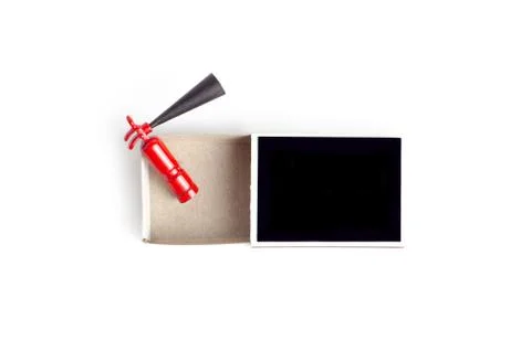 Tiny fire extinguisher inside an opened black match box, top view on white. Stock-Fotos