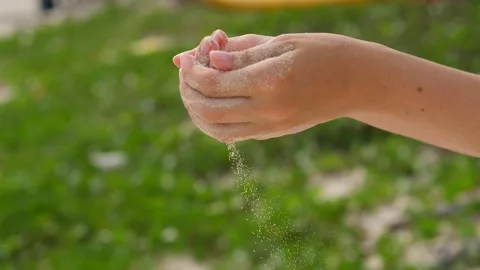 Tiny flow of sand grains fall down from woman hands, close up shot Stock Footage 150041050