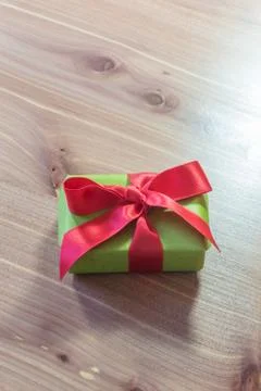 Tiny gift box wrapped in green paper with a big red satin bow, copy space Stock Photos