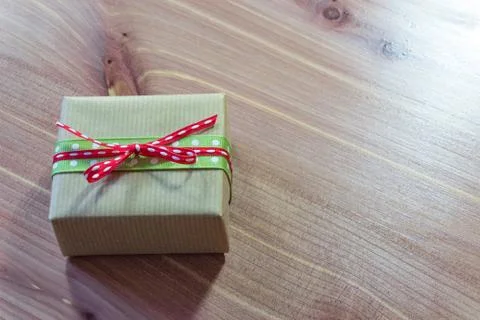 Tiny gift box wrapped in rustic brown kraft paper with red and green ribbons Stock Photos