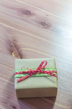 Tiny gift wrapped in green and red polka dot ribbon tied in a bow, copy space Stock Photos