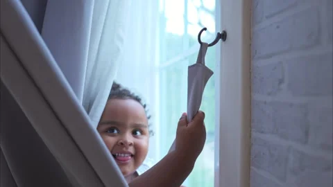 A tiny girl plays hide-and-seek with drapes in her bedroom Stock Footage 292794670