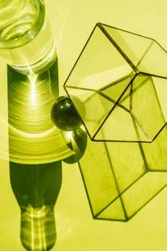Tiny glass cube, water bottle, steel sphere and their disproportionate shadows Stock Photos