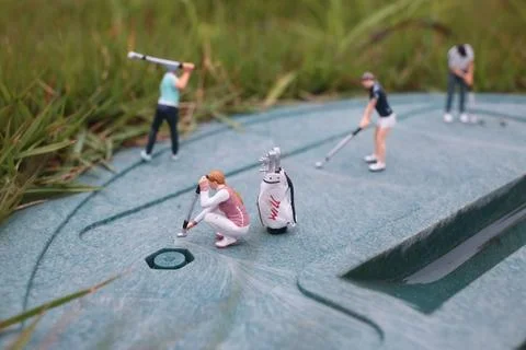 Tiny Golf Figurines Train Together On Textured Green Surface Foto stock