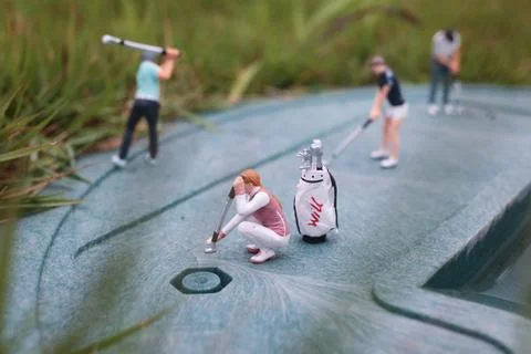 Tiny Golf Figurines Train Together On Textured Green Surface Foto stock