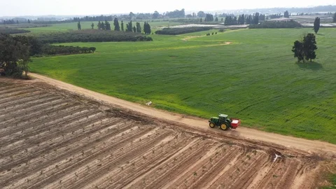 Tiny green tractor with red tank on his way Stock Footage 125912525