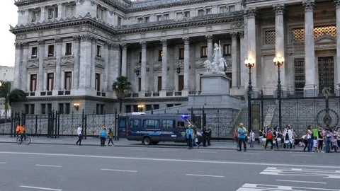 Tiny group of demonstrators playing drums in front of large congress building Stock Footage 100166133