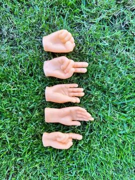 Tiny hands finger puppet toys showing different gestures placed on green gras Stock Photos