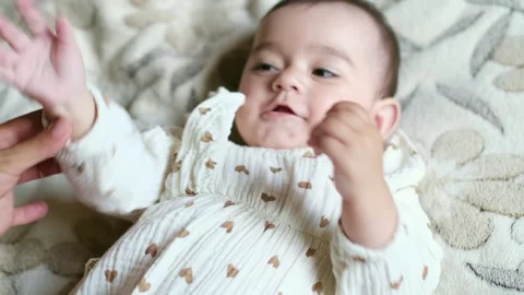 Tiny hands wave in the air, a baby's expression a blend of concentration and Stock Footage 257547059
