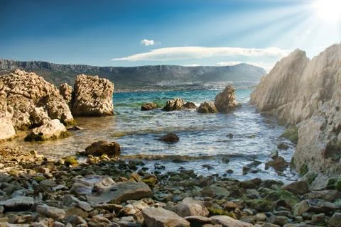 Tiny hidden beach surrounded by rocks on the shore of split, croatia. Sunligh Stock Photos
