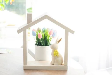 Tiny house of cozy home with Easter decor with rabbit and eggs on table of .. Foto stock