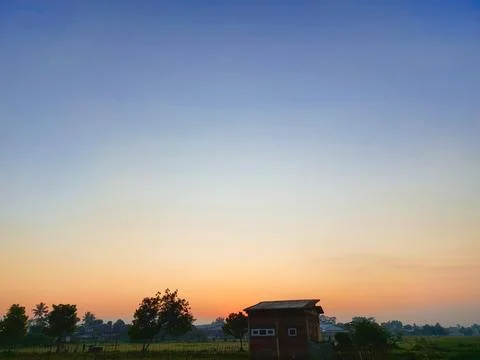Tiny house in rice paddy with setting sun. Stock Photos
