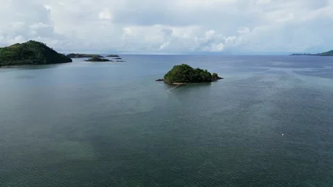 Tiny island with trees in the ocean on a cloudy day, aerial dolly forward Video stock 247428210