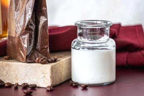 A tiny jar of milk on red table and pack of coffee on marble stone. Copy spac Stock Photos