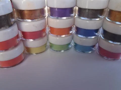 Tiny jars with white lids containing  multi coloured powders Stock Photos