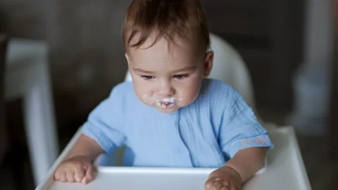 Tiny kid is fed by his mom. Sweet happy baby boy rejoices smiling adorably Stock Footage 212378427
