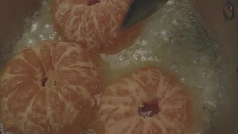 In a tiny kitchen miniature cookware holds three halved citrus fruits simmering Video stock 286901602