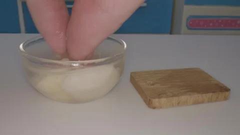 In a tiny kitchen setting hands immerse in a bowl of food while using miniature Video stock 286885613