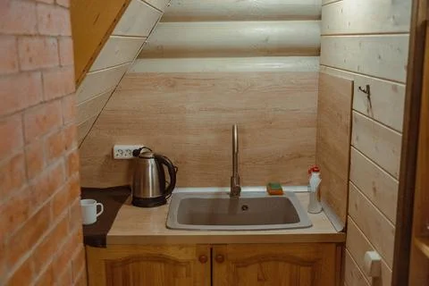 Tiny kitchenette with sink, kettle, and mug in wooden chalet Stock Photos