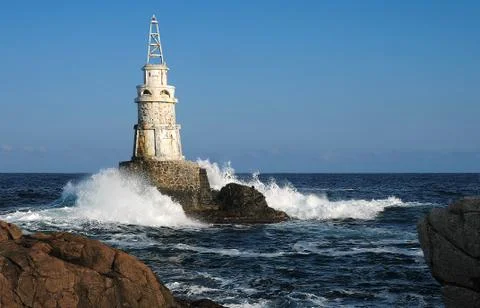 Tiny lighthouse and rough sea Stock Photos